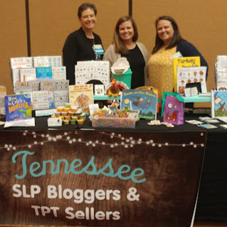 3 women standing behind table with educational products