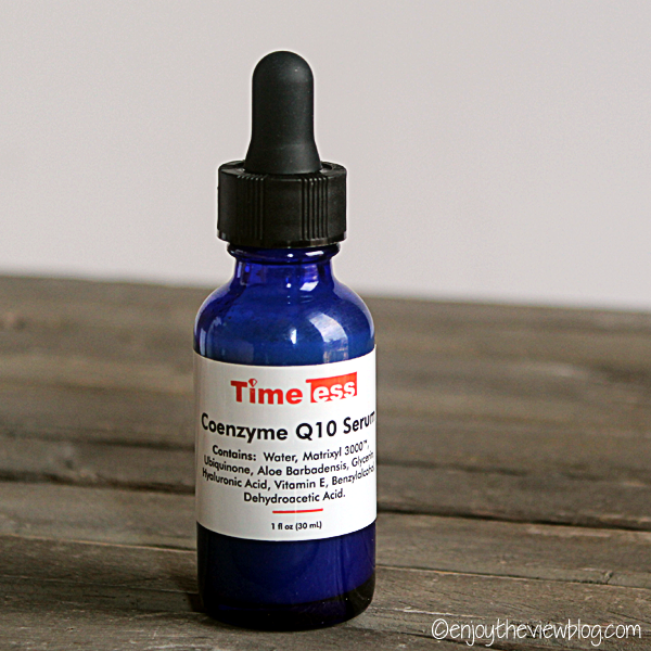 Blue glass bottle of Timeless CoQ10 Serum sitting on a wooden table 