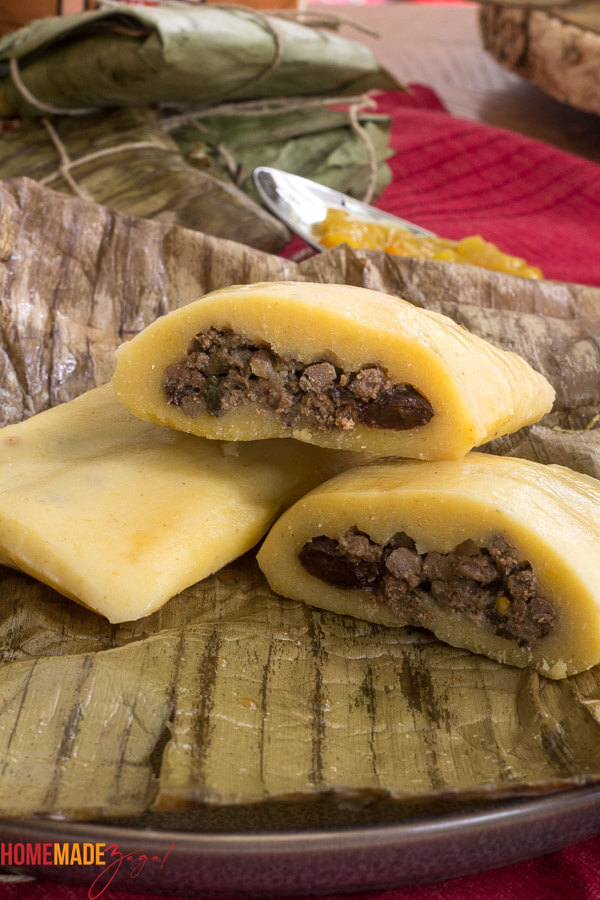Two pastelles on plate with banana leaf showing the inside with meat
