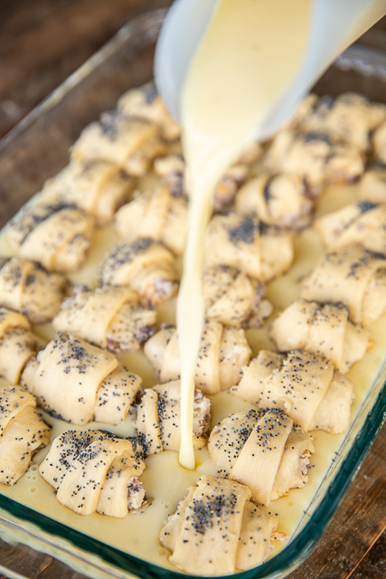 Ham & Cheese Crescent Breakfast Casserole - seriously the BEST!!! Crescent rolls, ham, cheese, brown sugar, Worcestershire sauce, cream cheese, dijon mustard, eggs, and milk. SO simple and SOOO delicious! Great for breakfast, brunch, lunch, dinner, and tailgating! Everyone LOVED this easy breakfast casserole. They cleaned their plates and asked for seconds. Success!!! #breakfast #casserole #ham #breakfastcasserole pouring egg and milk mixture into baking dish