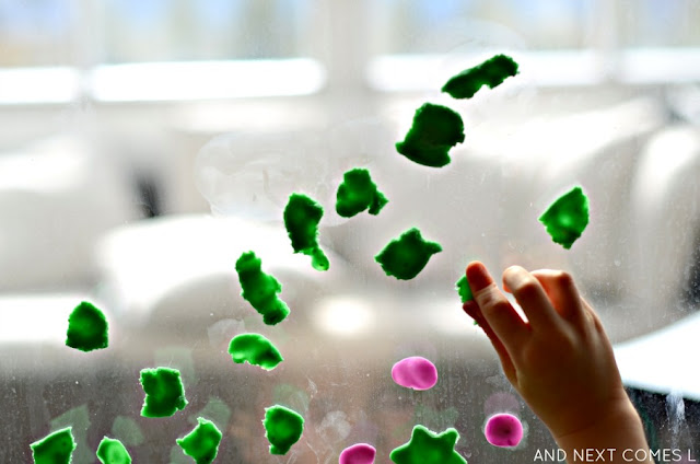 Child pressing pieces of play dough onto a window
