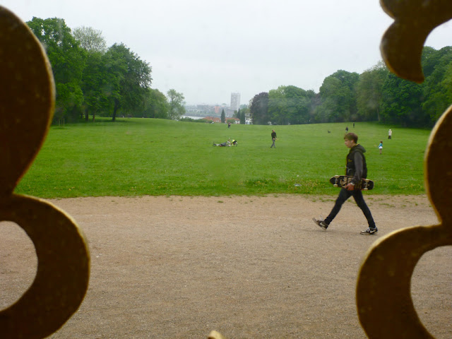 Blick in die Weite eines Parks, durch ein Fenstergitter hindurch aufgenommen