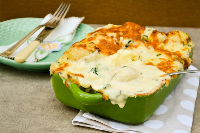 A comforting cauliflower cheese bake with a difference. Cauliflower and waxy baby potatoes in a cheese and spinach sauce topped with mozzarella and baked until golden. Veggie and vegan recipe.