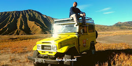 jeep wisata bromo warna kuning dengan latar gunung
