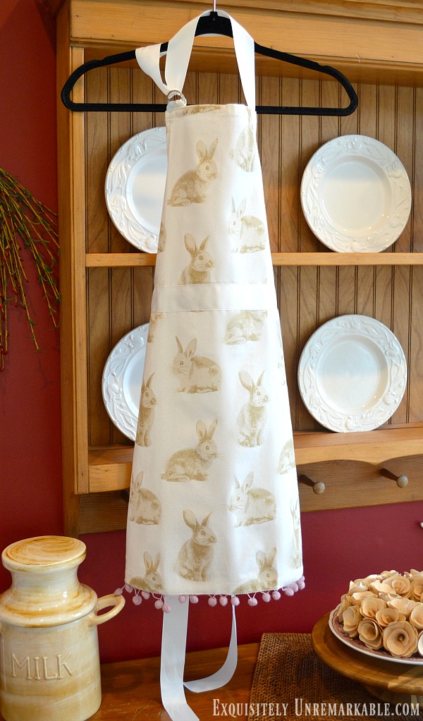 Full Length Bunny Apron hanging on pine plate rack with white plates