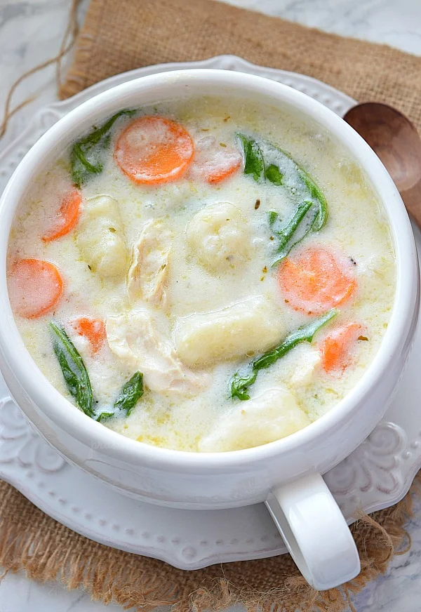 a white bowl with creamy chicken and gnocchi soup