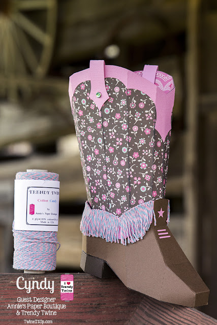 3d paper cowboy boot with a pink and blue twine fringe around the bottom half of boot