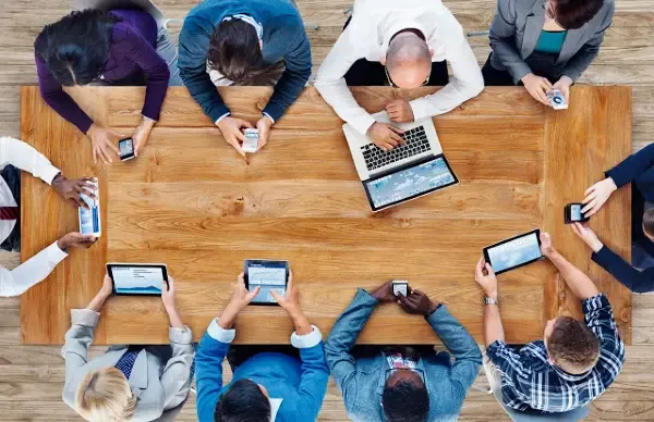 Top view of officemates holding their smartphones, tablets and laptops