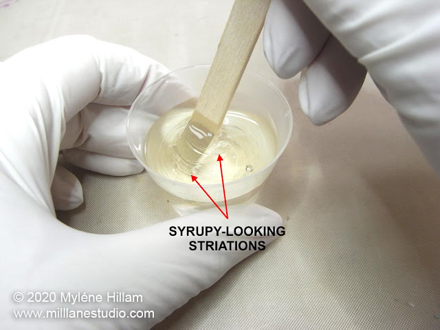 Syrupy striations in resin being mixed in a cup with a wooden stir stick