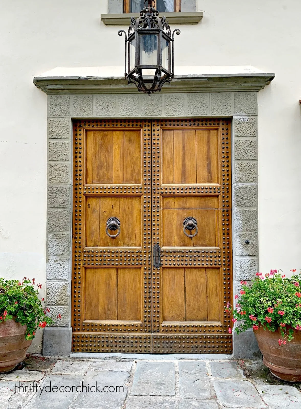 Tuscan wood doors with large metal light and pottery 