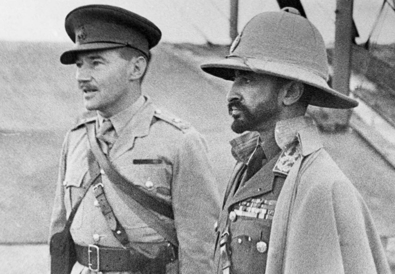 Haile Selassie (right), exiled Emperor of Ethiopia, whose empire was absorbed by Italy, returns with an Ethiopian army recruited to aid the British in Africa, on February 19, 1941. Here, the emperor inspects an airport, an interpreter at his side. On May 5, 1941, after the Italians in Ethiopia were defeated by Allied troops, Selassie returned to Addis Ababa, and resumed his position as ruler.