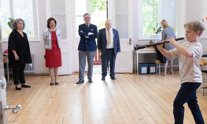 Queen Silvia wore a white tweed jacket and red dress from Chanel, and carried black leather clutch from Chanel