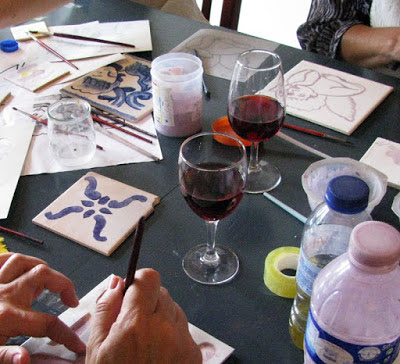 pintura de azulejos, um copo de vinho do porto, pinceis e tintas