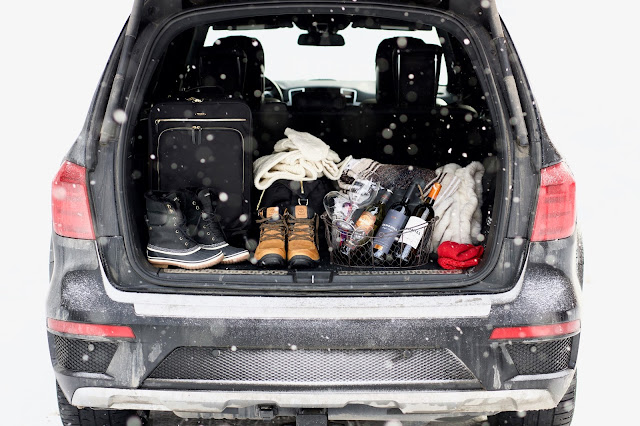 Mercedes Benz truck with the trunk open carrying Tumi luggage and wine