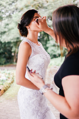 Maquilladora dándole los últimos retoques de maquillaje a la novia antes de la boda
