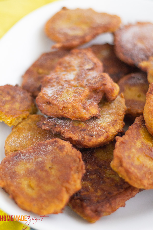 A full plate of fried pumpkin fritters, drizzled with sugar.