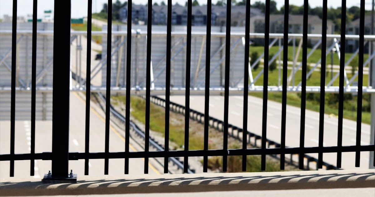 A Sleek black iron fence on a bridge over pass above interstate 70 in