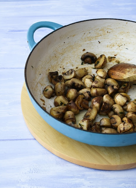 sauteed garlic mushrooms in a white cast iron frying pan