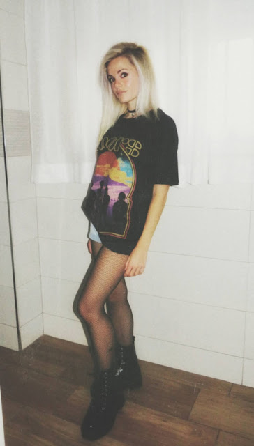 Estilo grunge con camiseta negra ancha con imagen del grupo The Doors, pantalón corto, medias de red pequeña, botas estilo militar y cazadora vaquera