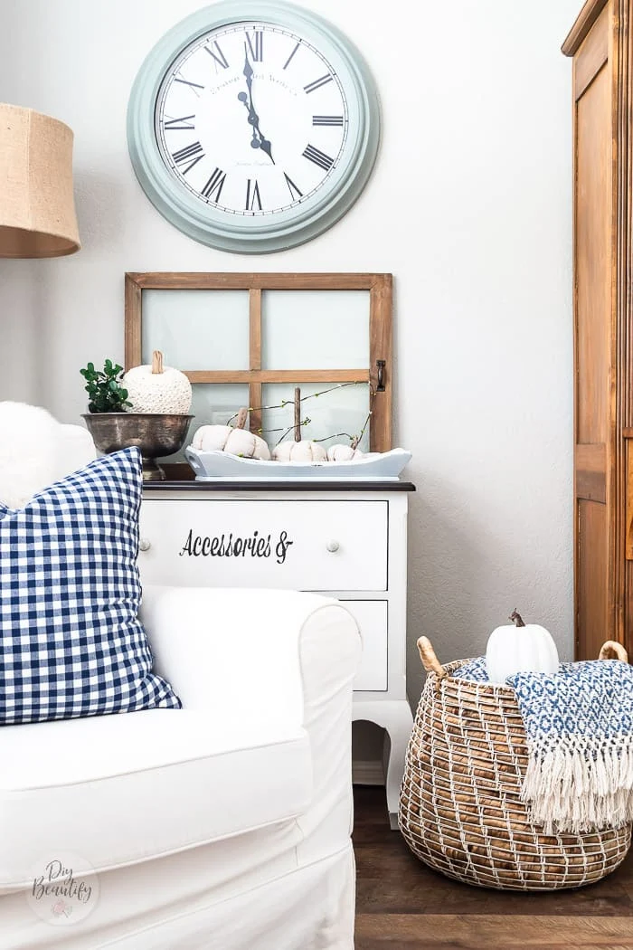blue gingham pillow on white chair, basket with blue throw and white pumpkin, vintage window and blue clock