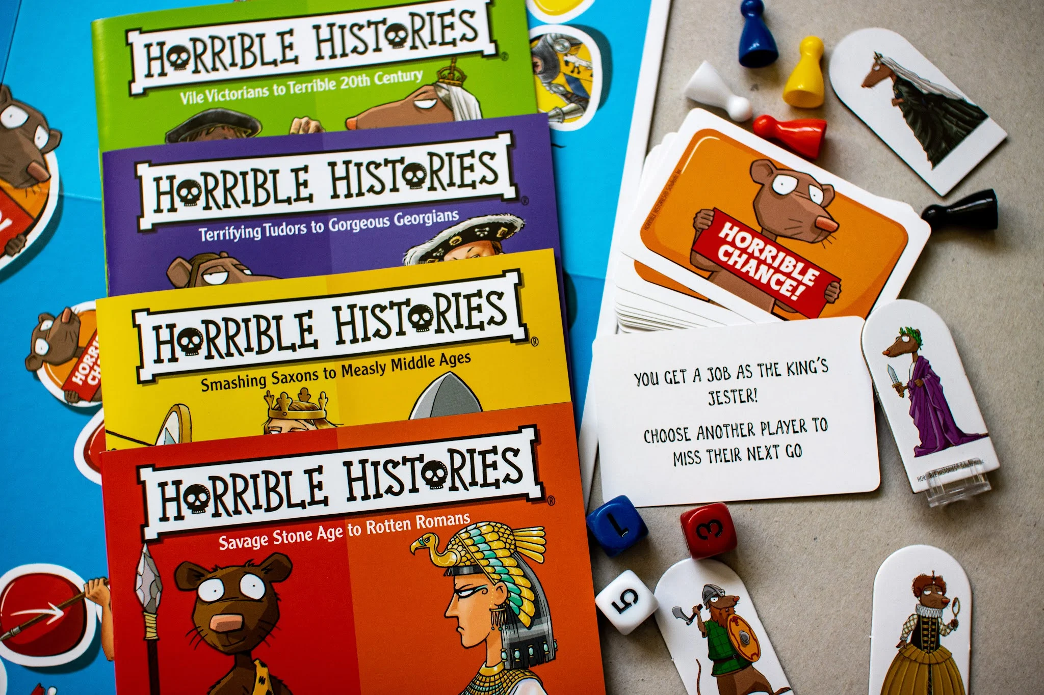Contents of the Horrible histories board game box including board, question booklet, character pieces and dice