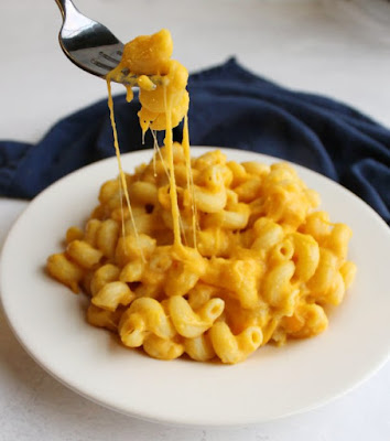 plate of acorn squash mac and cheese with cheese pull and bite on fork