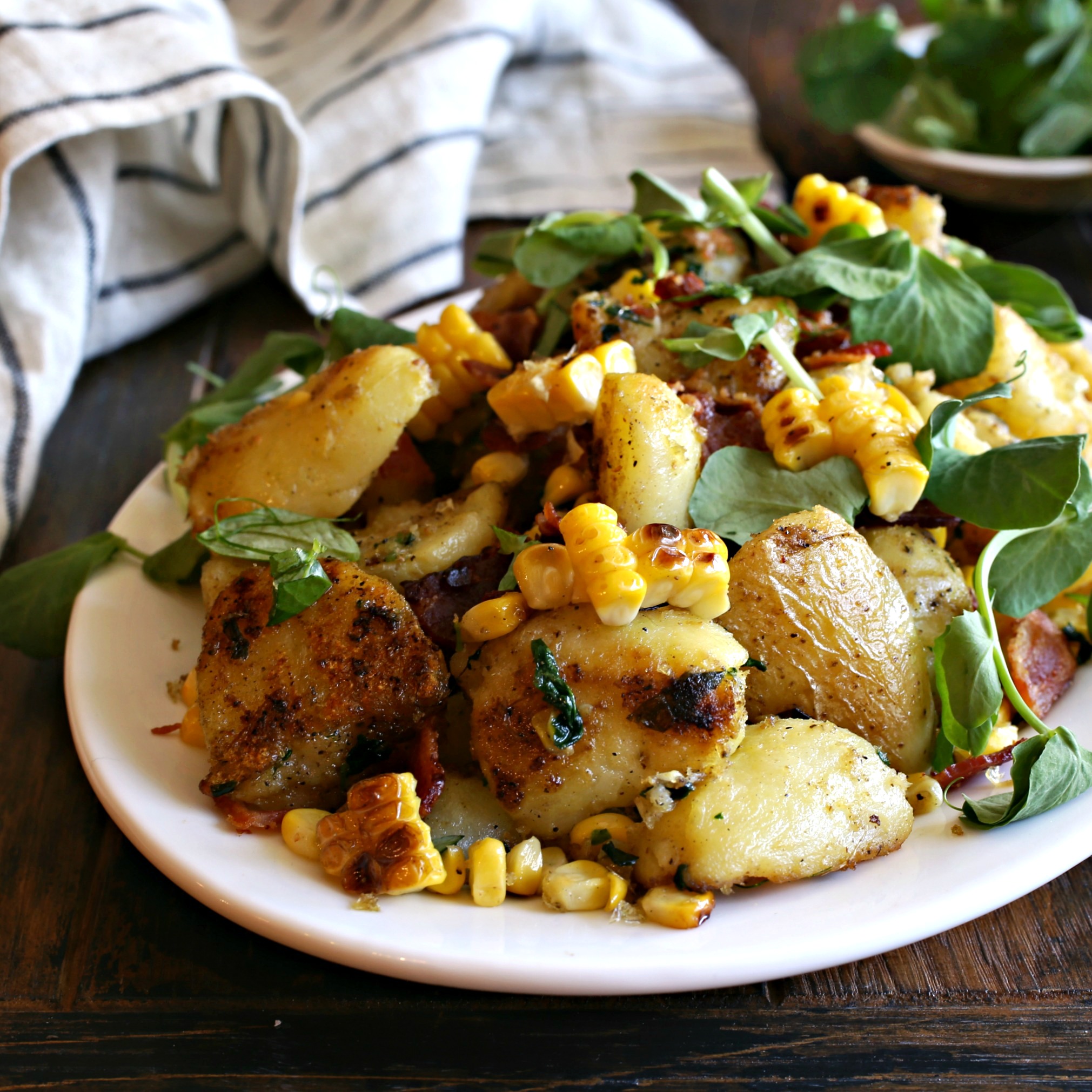 Recipe for a roasted potato salad with corn, bacon and an olive oil dressing.