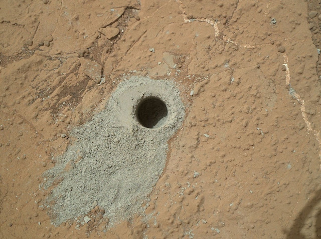Фотография с марсохода Curiosity, сделанная им во время миссии на Марсе. Curiosity просверливает отверстия в марсианской почве, чтобы взять пробы и образцы для тестирования.