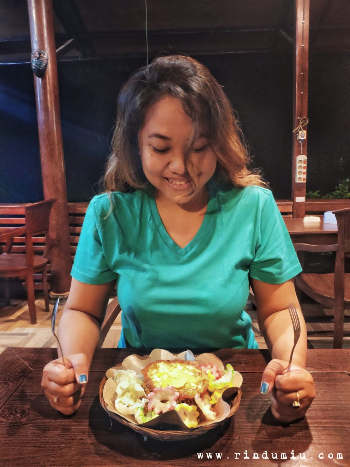 A woman is ready to eat Sego Thiwul Goreng served with a bull's eye egg, some colorful kerupuk, and slices of cabbage at Kopi Plosok cafe in Sleman Jogja