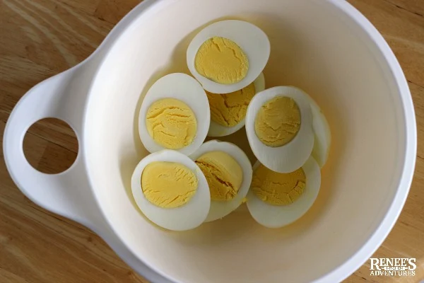 hard boiled eggs in a white bowl, halved and ready for Sweet Relish Deviled Eggs by Renee's Kitchen Adventures