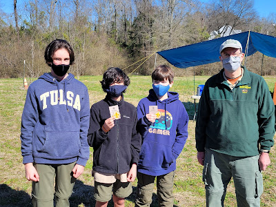 Blake (center, left) and Cooper (center, right) show off their new Scout ranks after receiving them from Senior Patrol Leader Will (far left) and Scoutmaster Baird (far right).