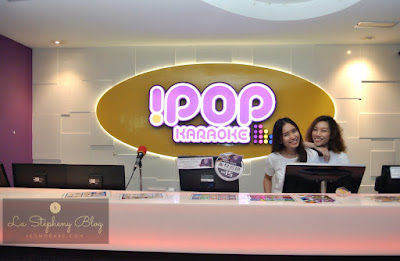 two girls standing at the reception table of the karaoke box iPOP setapak kuala lumpur smiling at the audience