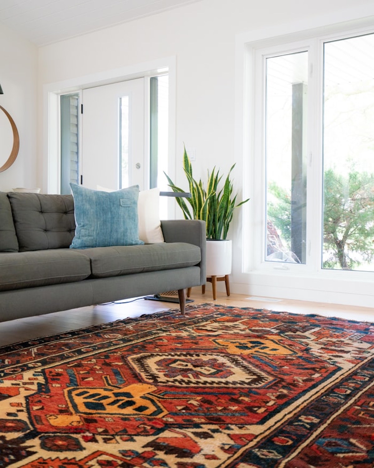 Salón con alfombra étnica y sofá de respaldo bajo en tonos grises