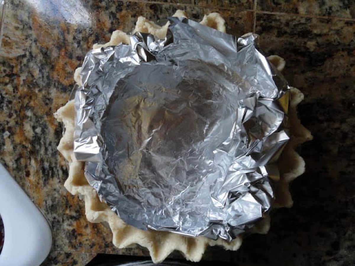 A flaky pie crust shell lined with foil for Lemon Meringue Pie.