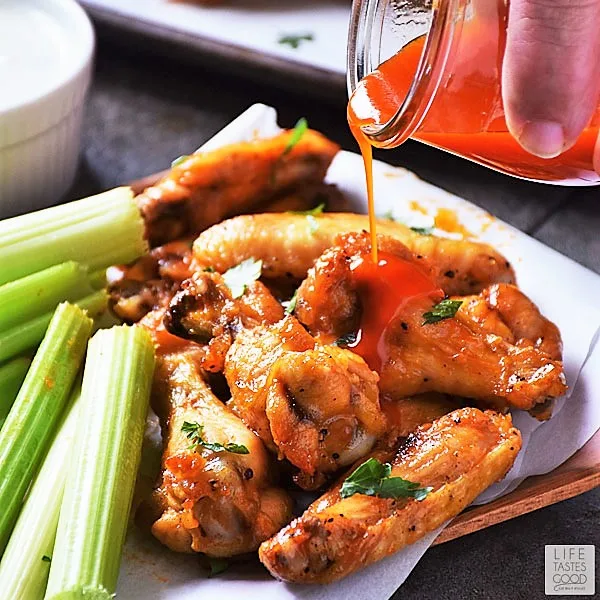 Pouring extra Buffalo wing sauce on Low Carb Buffalo Wings appetizer