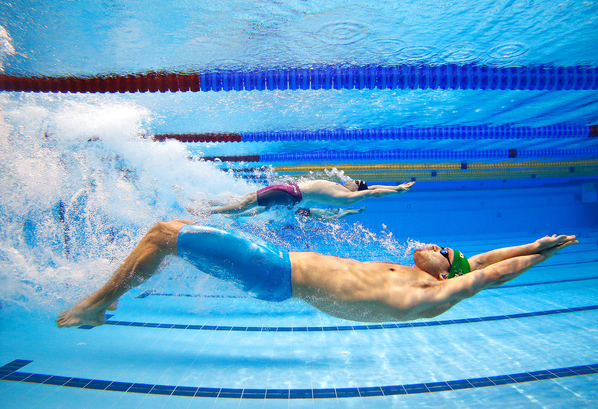 Спортсмен занимающийся плаванием. Плавать в бассейне. Мужчина плавает в бассейне. Пловец в бассейне.
