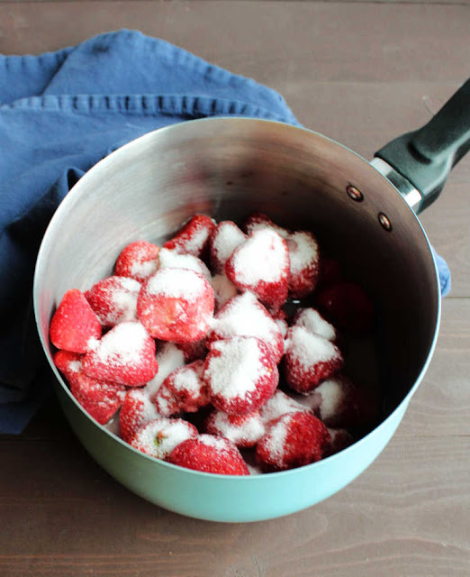 strawberry topping mixture ingredients strawberries, sugar and lemon juice in saucepan ready to make sauce