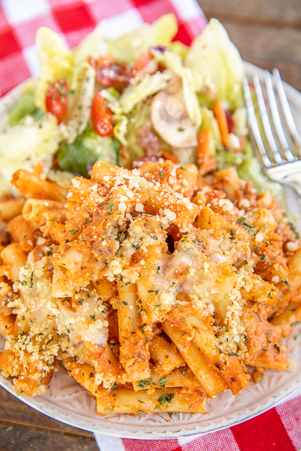The ULTIMATE Baked Ziti - copycat Olive Garden Baked Ziti Al Forno. SUPER easy to make and tastes AMAZING! Ziti pasta, Italian sausage, spaghetti sauce, Alfredo sauce, mozzarella, provolone, ricotta, parmesan, panko bread crumbs, garlic, and olive oil. Can make in advance and refrigerate or freeze for later. Hands down the best pasta casserole we've ever eaten! #pasta #casserole #olivegarden #bakedziti #freezermeal baked ziti and salad on a plate