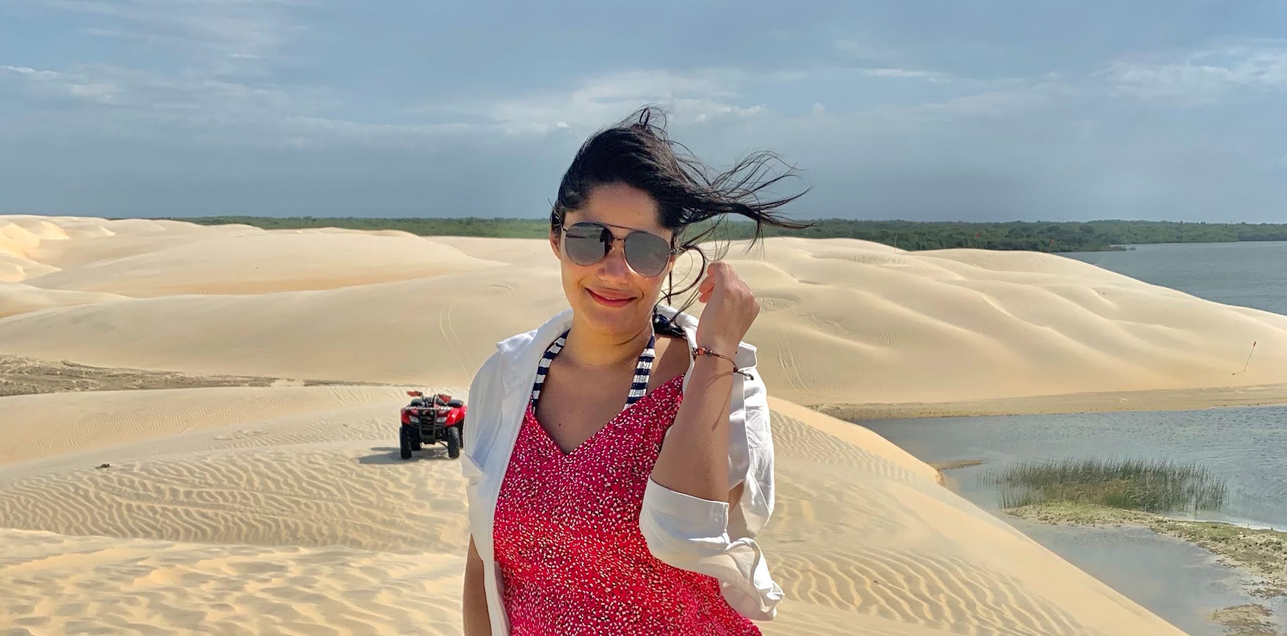 lencois piauienses na rota das emocoes mulher morena, jovem, cabelo preto, oculos escuros, blusa rosa e blaser branco em um oasis