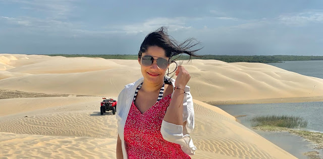 lencois piauienses na rota das emocoes mulher morena, jovem, cabelo preto, oculos escuros, blusa rosa e blaser branco em um oasis