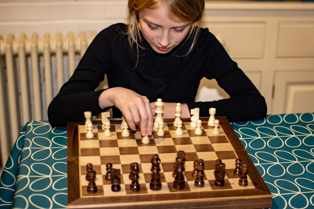 a 10 year old girl in black top about to start playing chess