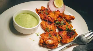 Chicken tikka on a serving plate with green chutney