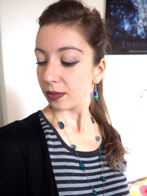 Hades inspired Disneybound villain outfit jewellery details of blue stone square dangly earrings and long blue glass necklace, with cool toned makeup and high ponytail
