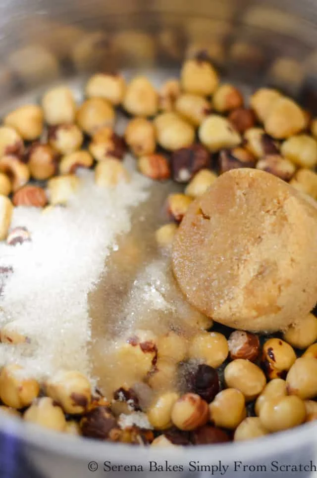 Peeled Hazelnuts in pan with brown sugar, granulared sugar, and water.
