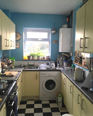 A blue and yellow kitchen with a chequerboard floor