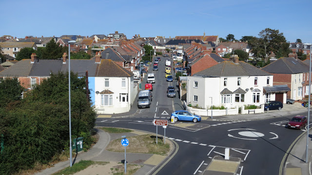 Houses, road, cars, roundabout and blue sky.