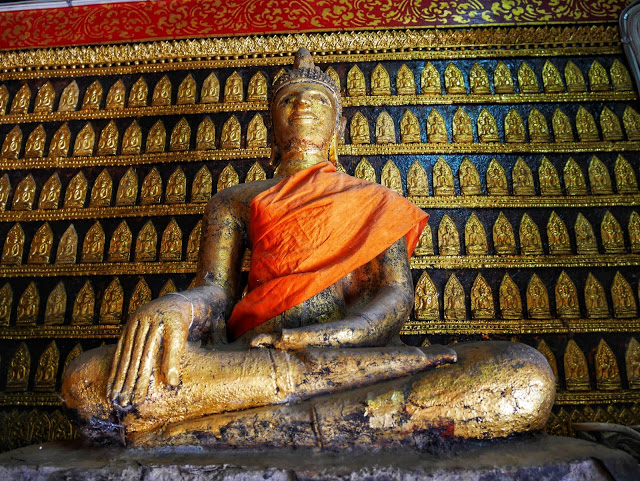 a seated buddha statue wrapped in a saffron cloth