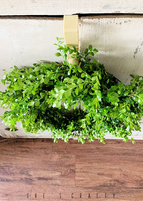 Hanging boxwood wreath in antique cabinet doors.