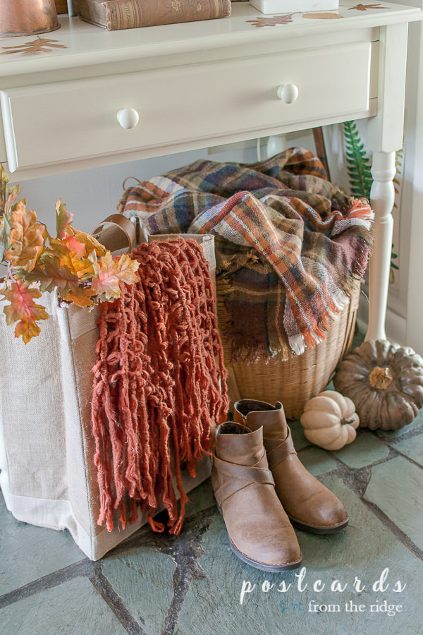 plaid blanket in a large basket with boots on the floor