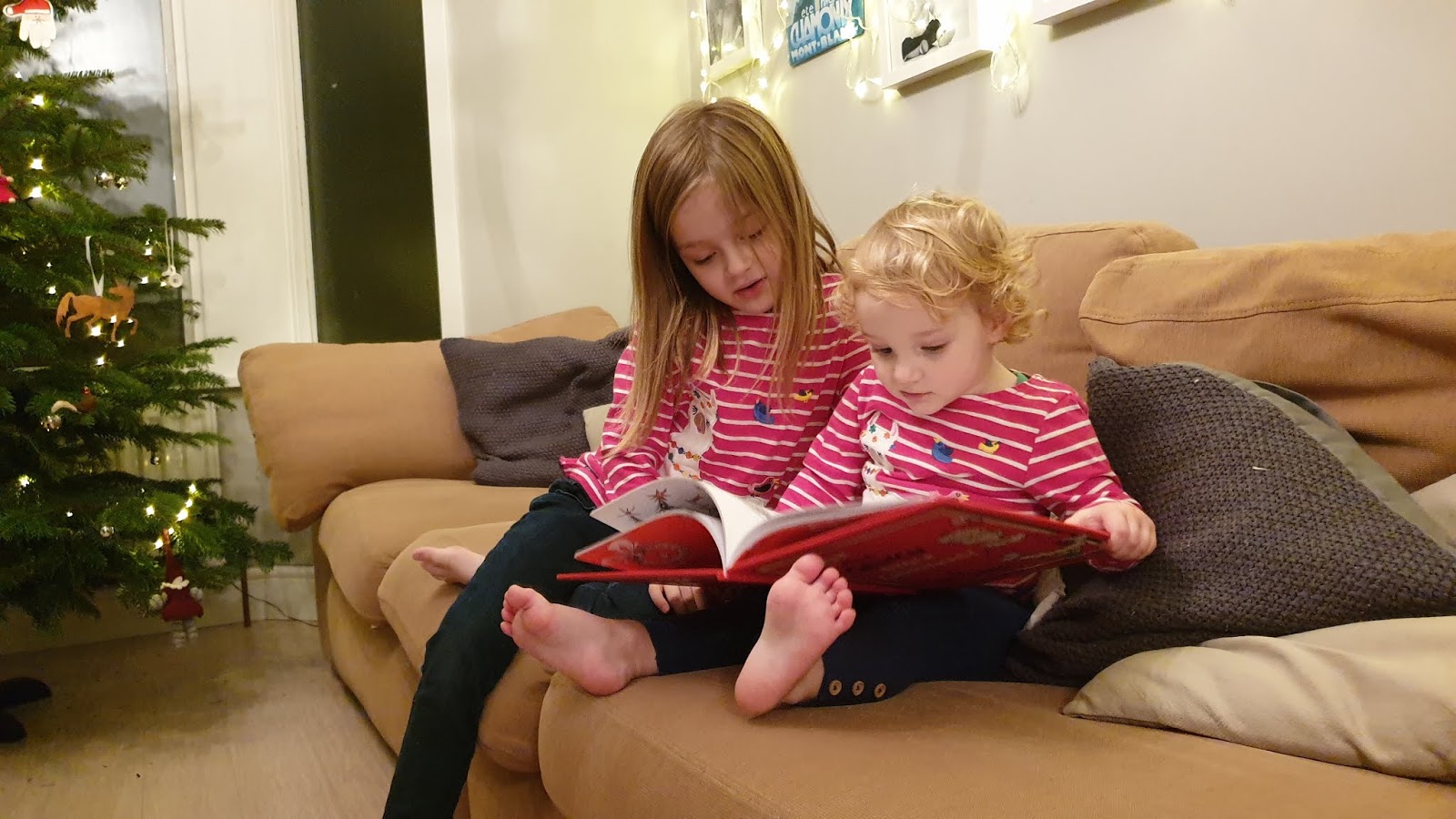 sisters sitting on a sofa reading a book